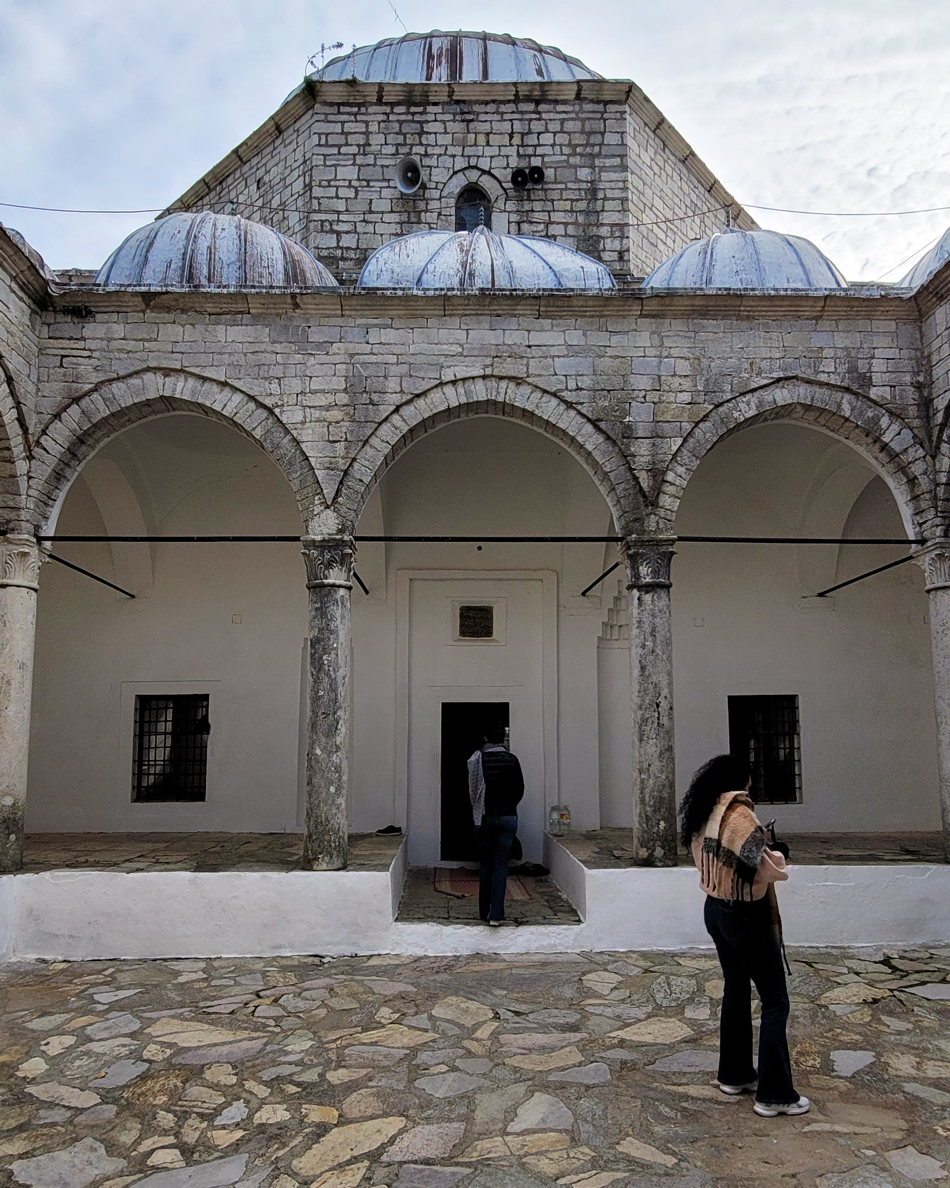The entrance courtyard of the Lead Mosque in Albania , with visitors exploring the historic site.