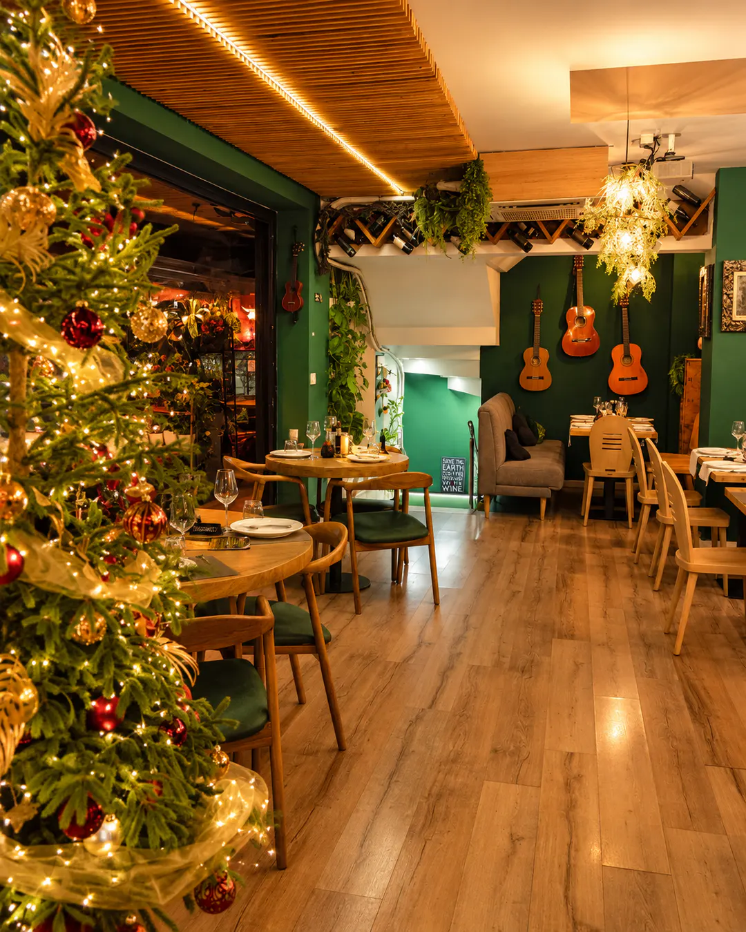 Atmosferë festive ngrënieje te Fresh Garden Restaurant në Tiranë, me pemë Krishtlindjesh të zbukuruar, tavolina elegante, mobilie druri dhe ndriçim të ngrohtë.