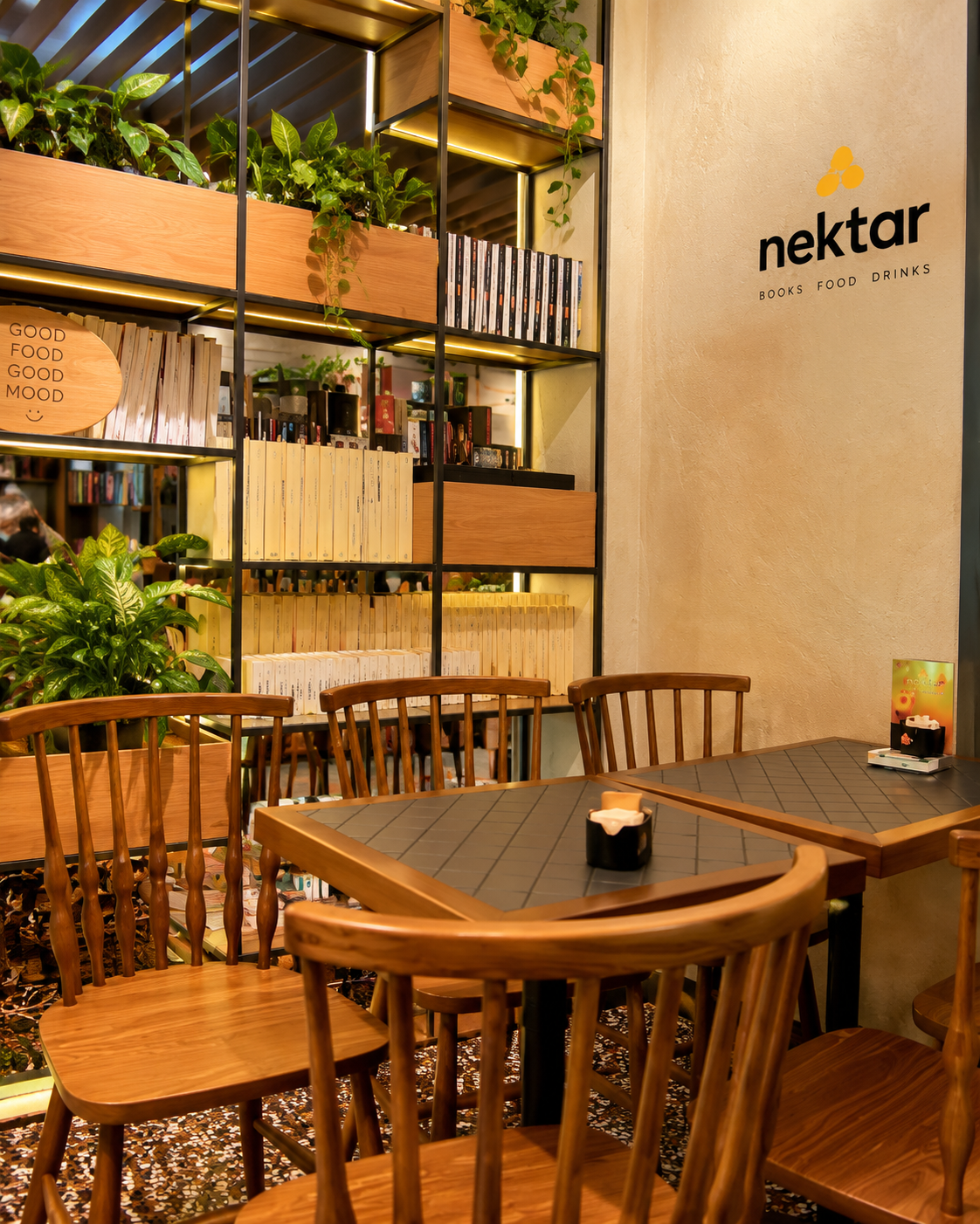 Ambient i brendshëm komod i Nektar Bookcafé në Tiranë me rafte librash dhe ndenjëse prej druri