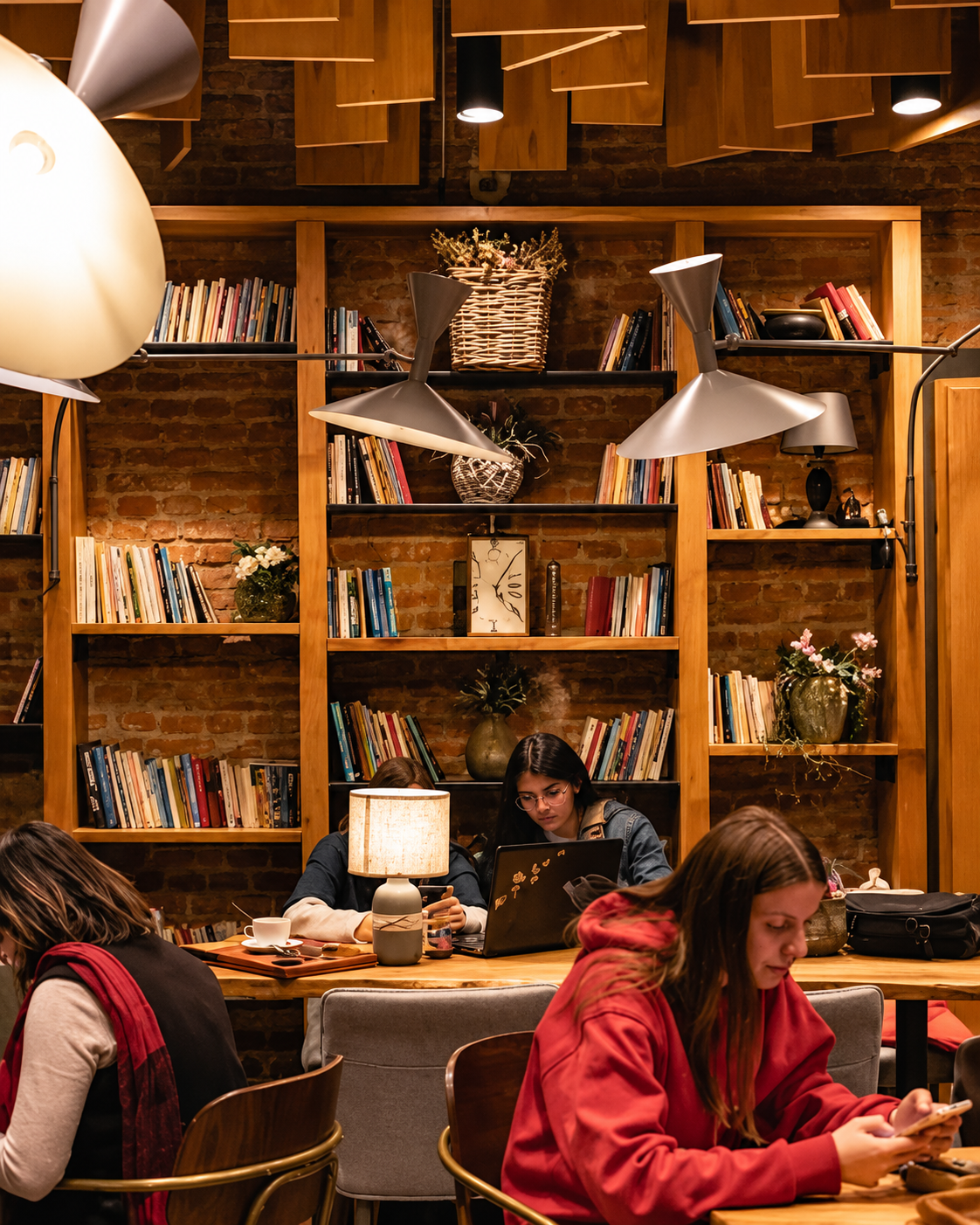 Zonë leximi në Mulliri i Vjetër në Tiranë me rafte librash dhe klientë që shijojnë kafenë
