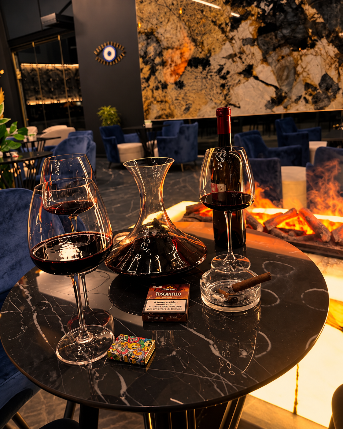 Red wine and decanter on a table beside a fireplace at a wine bar in Tirana
