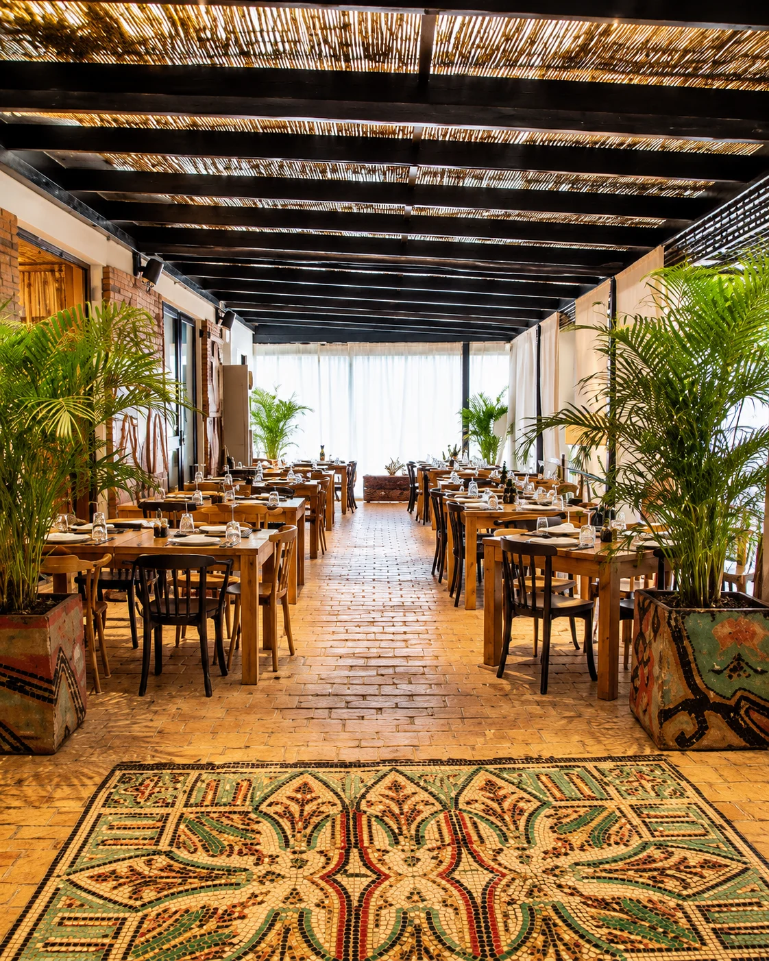 Ristorante tradizionale di fattoria con tavoli in legno, arredamento rustico e terrazza coperta alla Ferma 100 di Vishaj, Tirana.