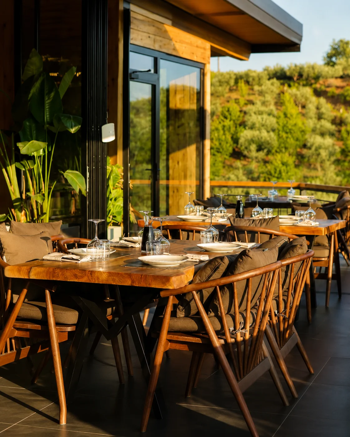 Terrazza rustica all'aperto con tavoli in legno e vista sulla campagna alla Ferma Çollaku vicino a Tirana, Albania.