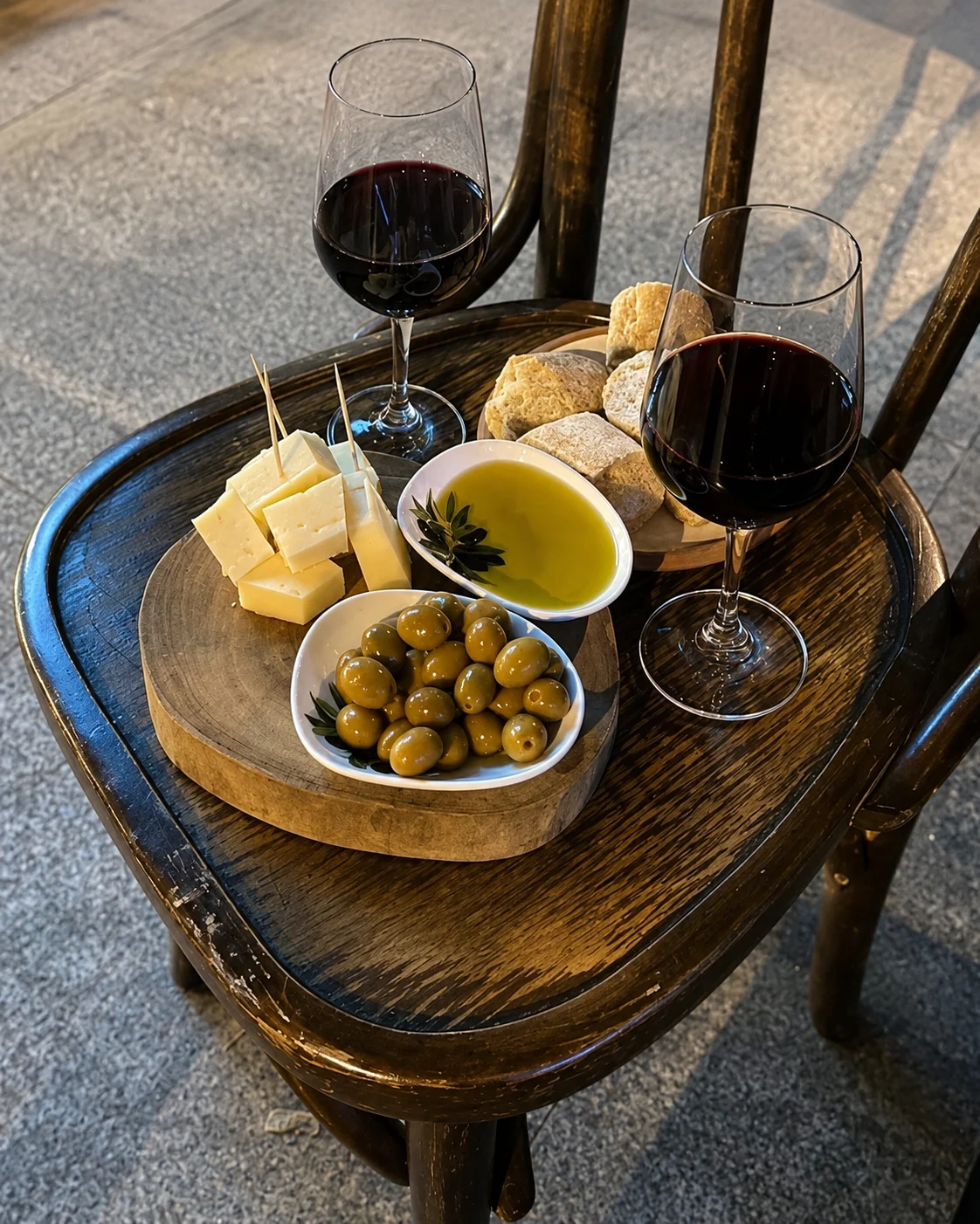 Due bicchieri di vino rosso con formaggio locale, olive e olio d'oliva alla Ferma Lisat vicino a Tirana.