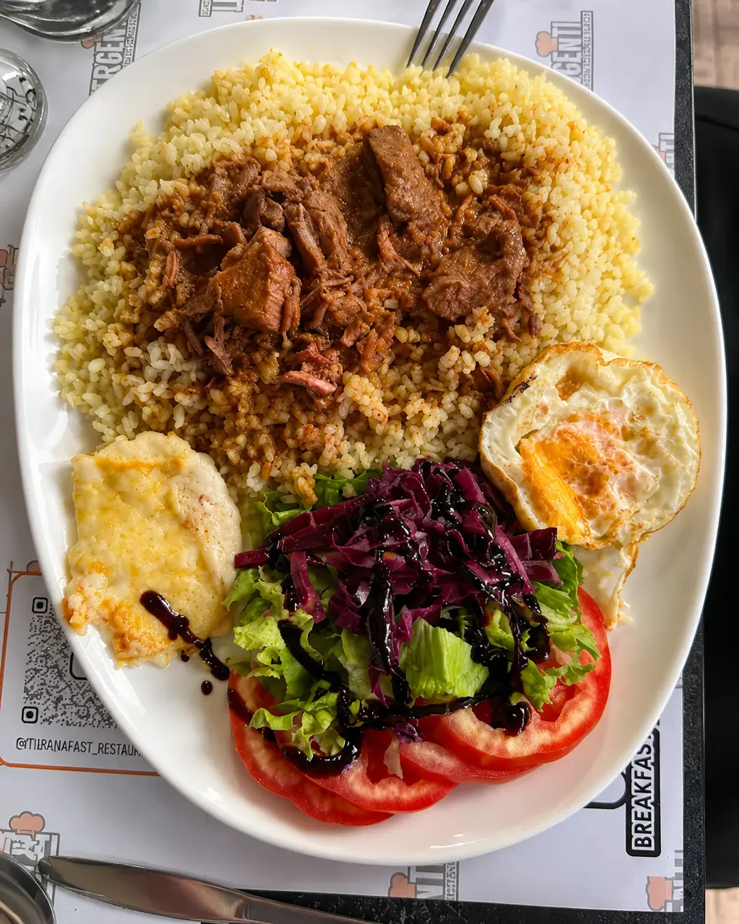 Vakt tradicional shqiptar me oriz, mish të gatuar ngadalë, vezë të skuqur dhe sallatë me lakër të kuqe në Genti Breakfast & Restaurant.
