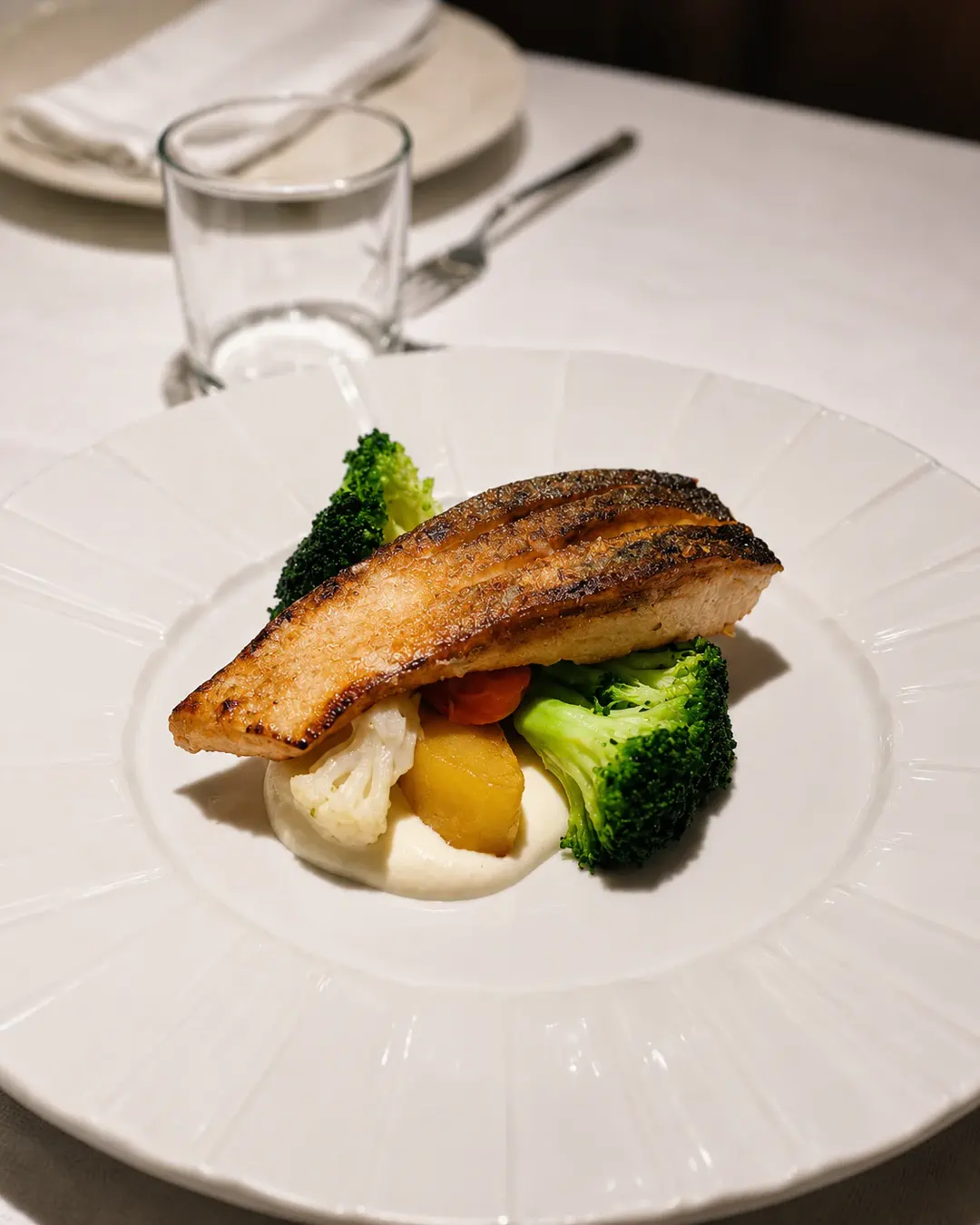 Fileto peshku në skarë, e servirur me brokoli, patate, lulelakër dhe salcë kremoze në Idromeno Restaurant.