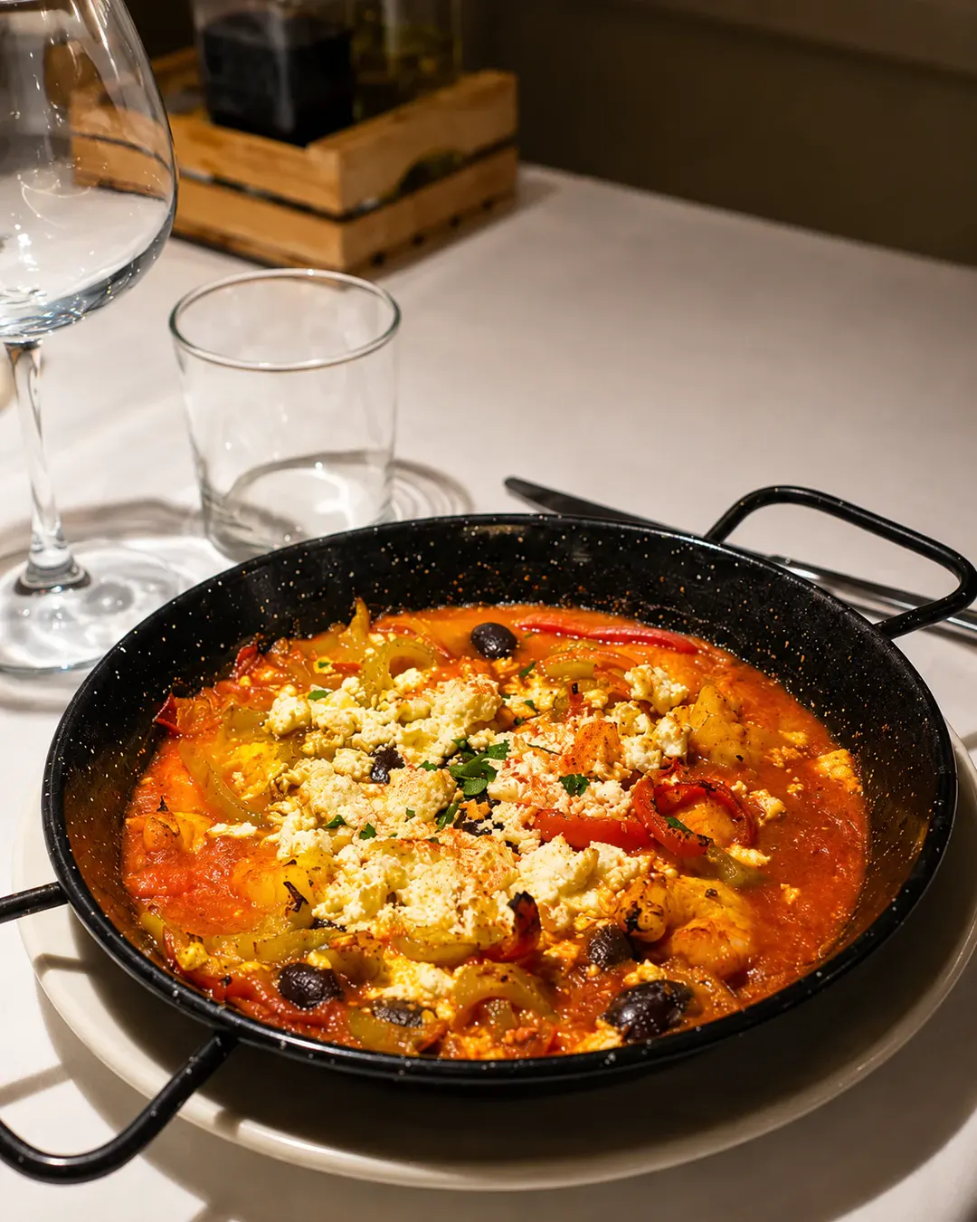 Gatim tradicional mesdhetar me djathë feta të pjekur, speca, ullinj dhe salcë domatesh, i servirur në tigan në Idromeno Restaurant.