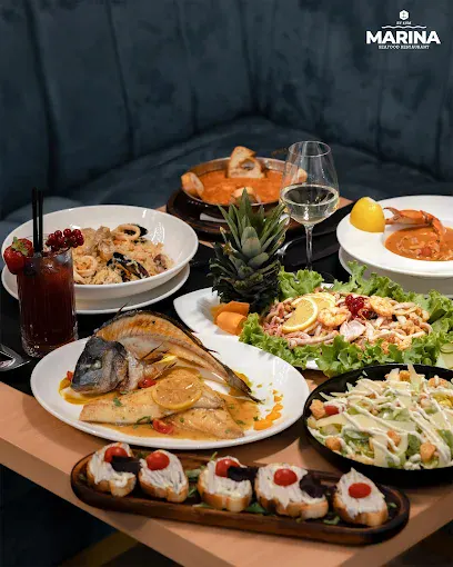 Tavolinë me gatime frutash deti, peshk në skarë, makarona me fruta deti, karkaleca, sallata dhe antipasta në restorantin Marina Seafood by 4VM.