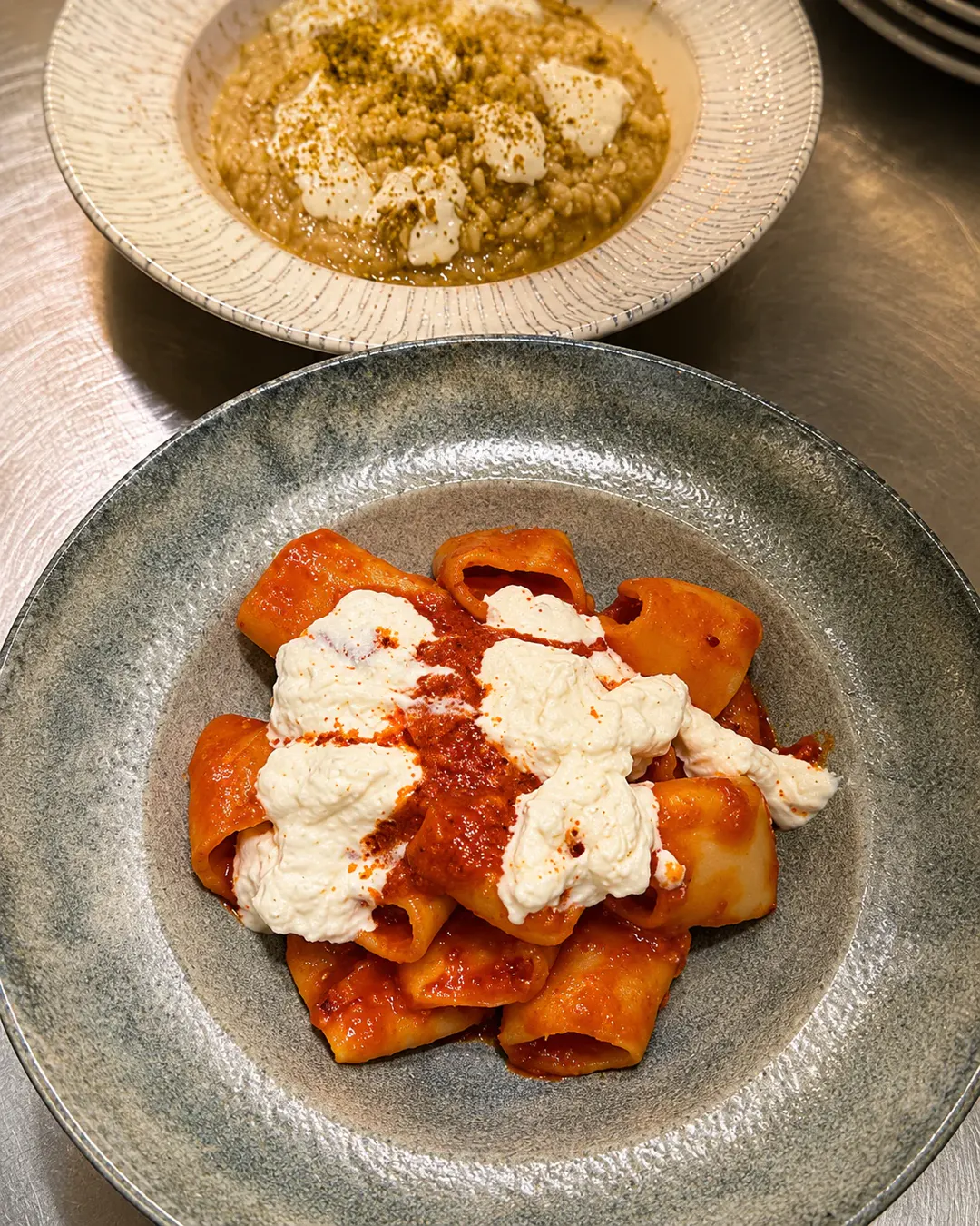 Makarona paccheri me salcë domatesh dhe burrata kremoze, të shoqëruara me një pjatë rizotoje në Pasta e Vino.