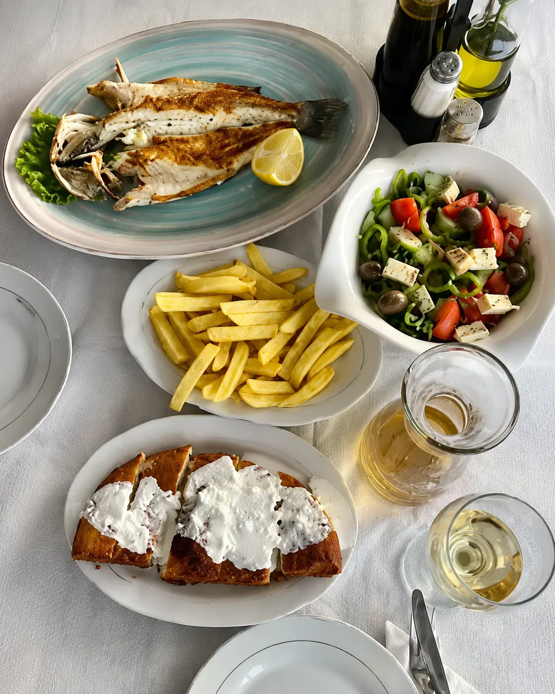 Peshk i plotë në skarë, i servirur me limon, patate të skuqura, sallatë greke me djathë feta dhe bukë tradicionale në Restorant Aleksi.