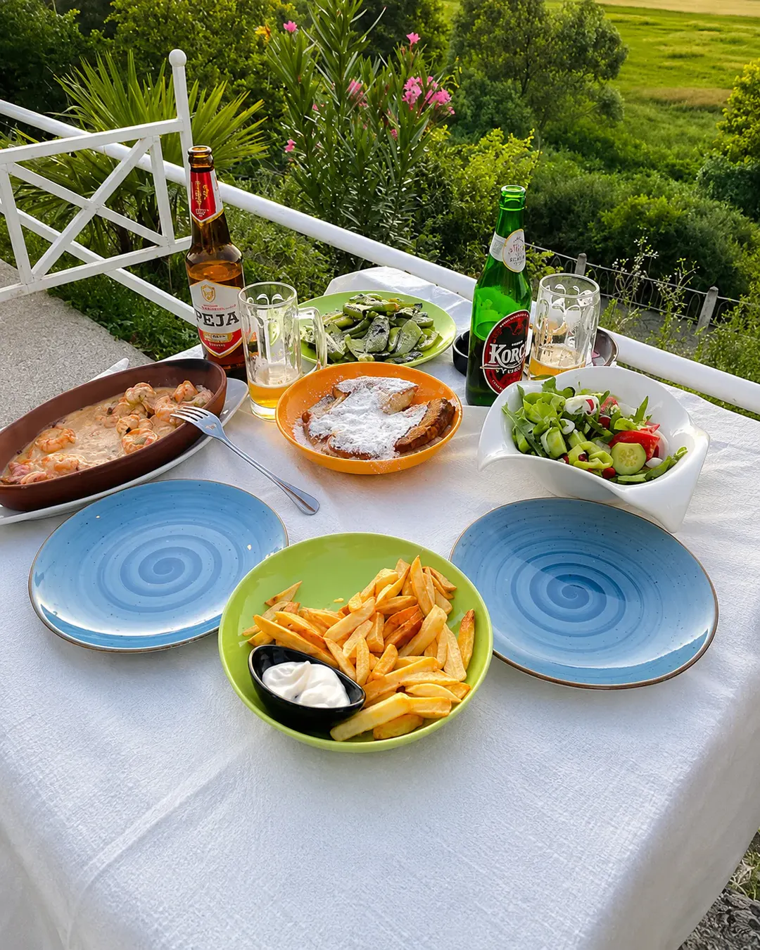 Ambient i jashtëm për të ngrënë në Restorant Aleksi, me karkaleca deti, sallatë të freskët, patate të skuqura, gatime tradicionale dhe pamje nga natyra e gjelbër.