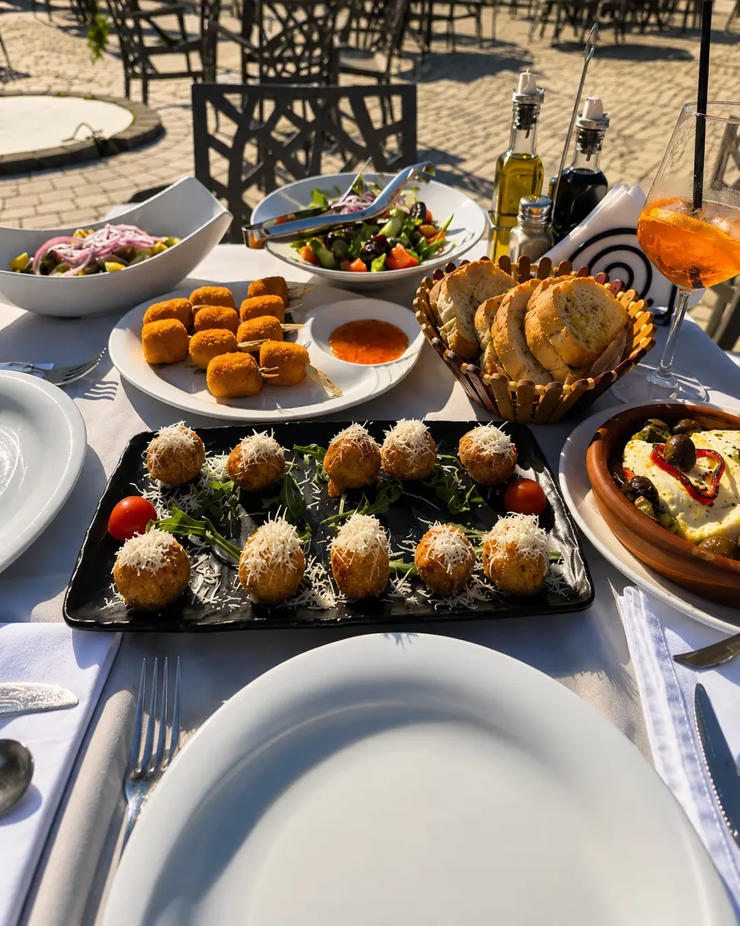 Përzgjedhje mezesh tradicionale, ushqimesh të skuqura, sallatash të freskëta dhe buke, të servirura në ambientin e jashtëm të Shkodra Lake Restaurant.