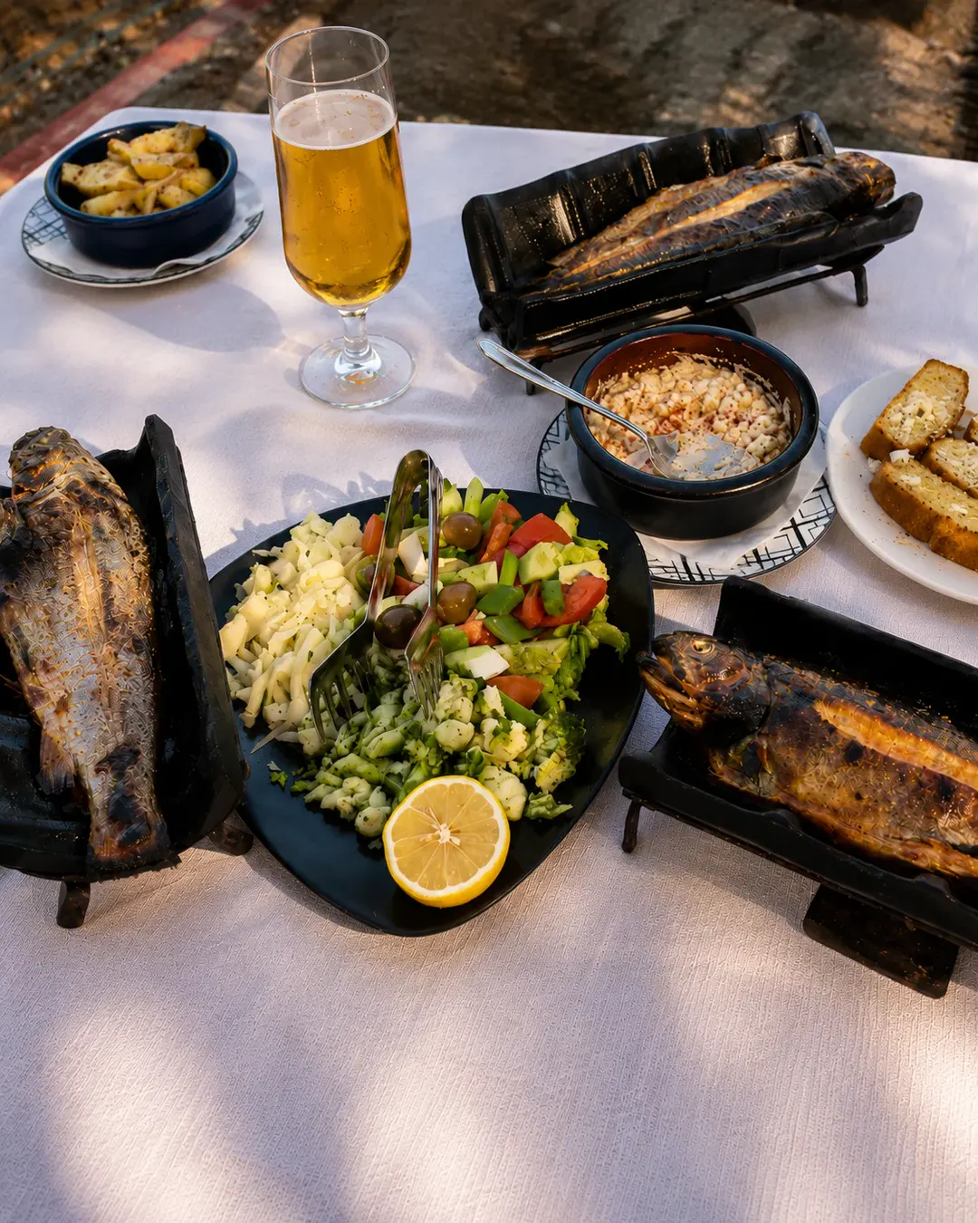 Peshk i plotë në skarë, i servirur me sallatë të freskët, djathë, limon dhe garnitura tradicionale në Taverna Shkodrane në Shkodër, Shqipëri.