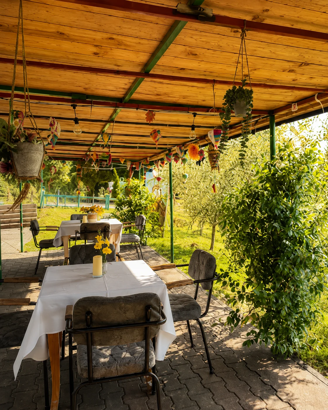 Terrazza rustica coperta del ristorante, circondata dal verde, alla Turtle Farm Albania vicino a Petrelë, Tirana.