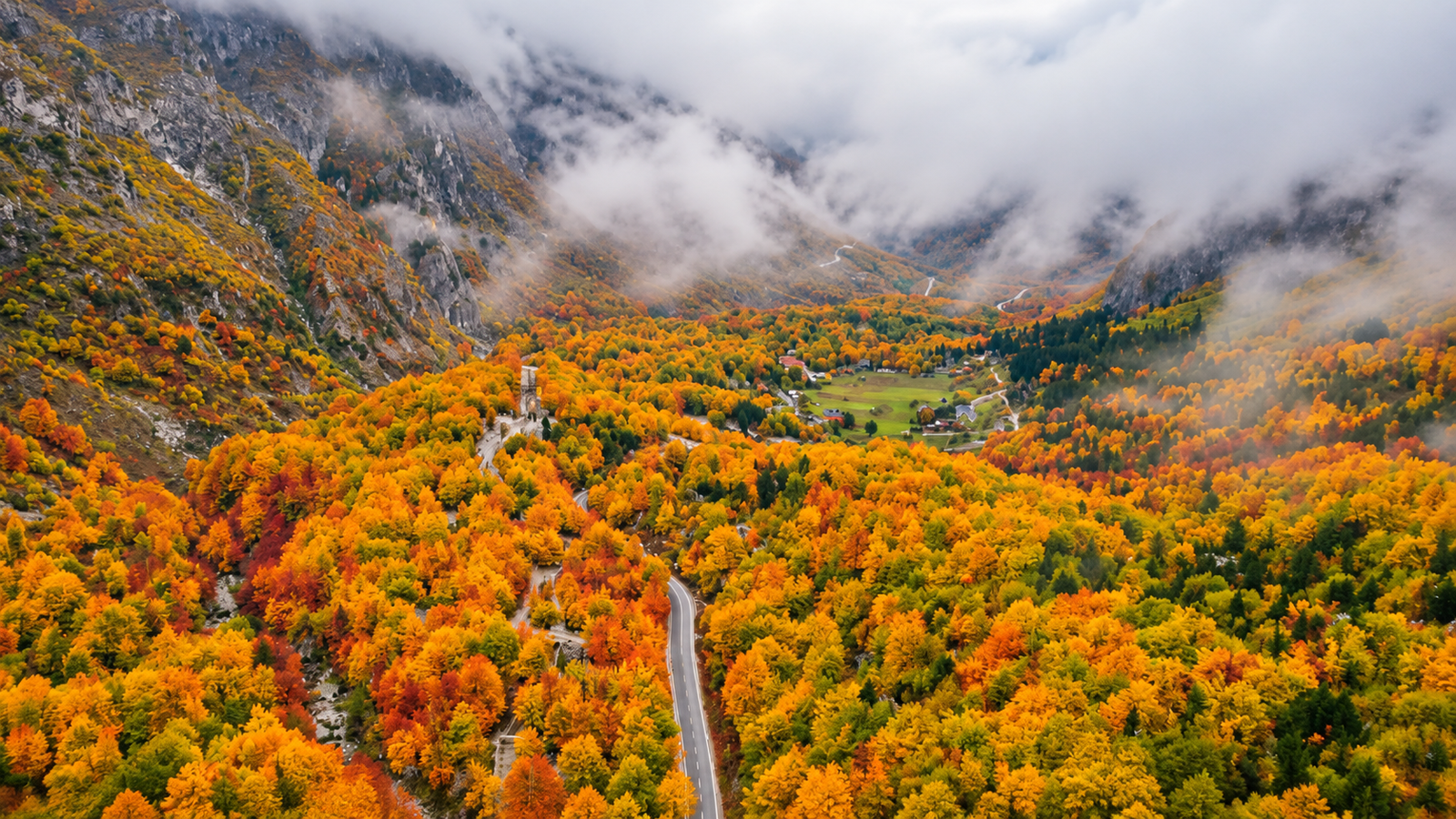 Passo Valbona–Theth in autunno con boschi colorati e montagne avvolte dalla nebbia nelle Alpi Albanesi