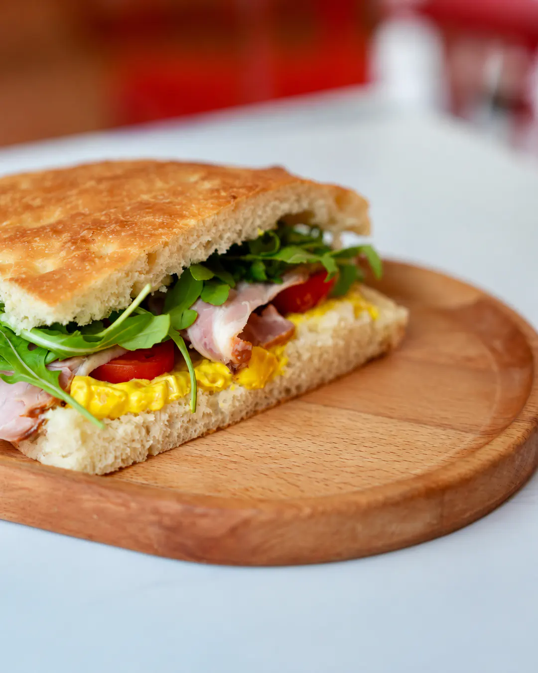 Sanduiç me focaccia të sapopjekur, i mbushur me sallame italiane, rukola, domate dhe salcë kremoze te Ambrosso në Tiranë.
