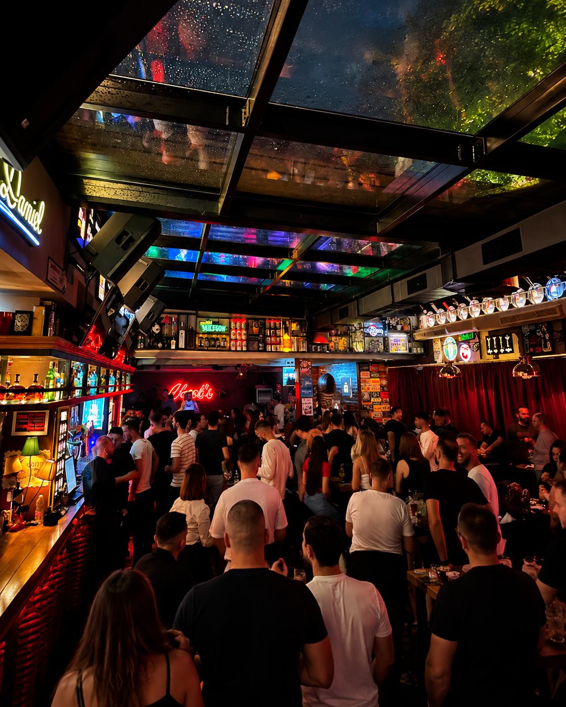 Crowded evening at Charl's Bistro in Tirana, Albania, featuring colorful lighting, a lively bar and nightlife atmosphere.