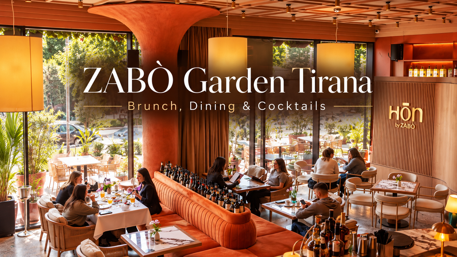 Interior of ZABÒ Garden in Tirana, featuring warm terracotta tones, elegant seating, large windows, and guests enjoying the restaurant's atmosphere.