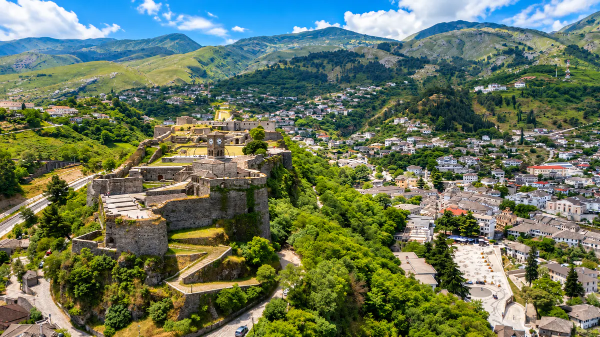 Pamje ajrore e Kalasë së Gjirokastrës mbi qytetin historik të gurtë dhe malet përreth në Shqipëri.