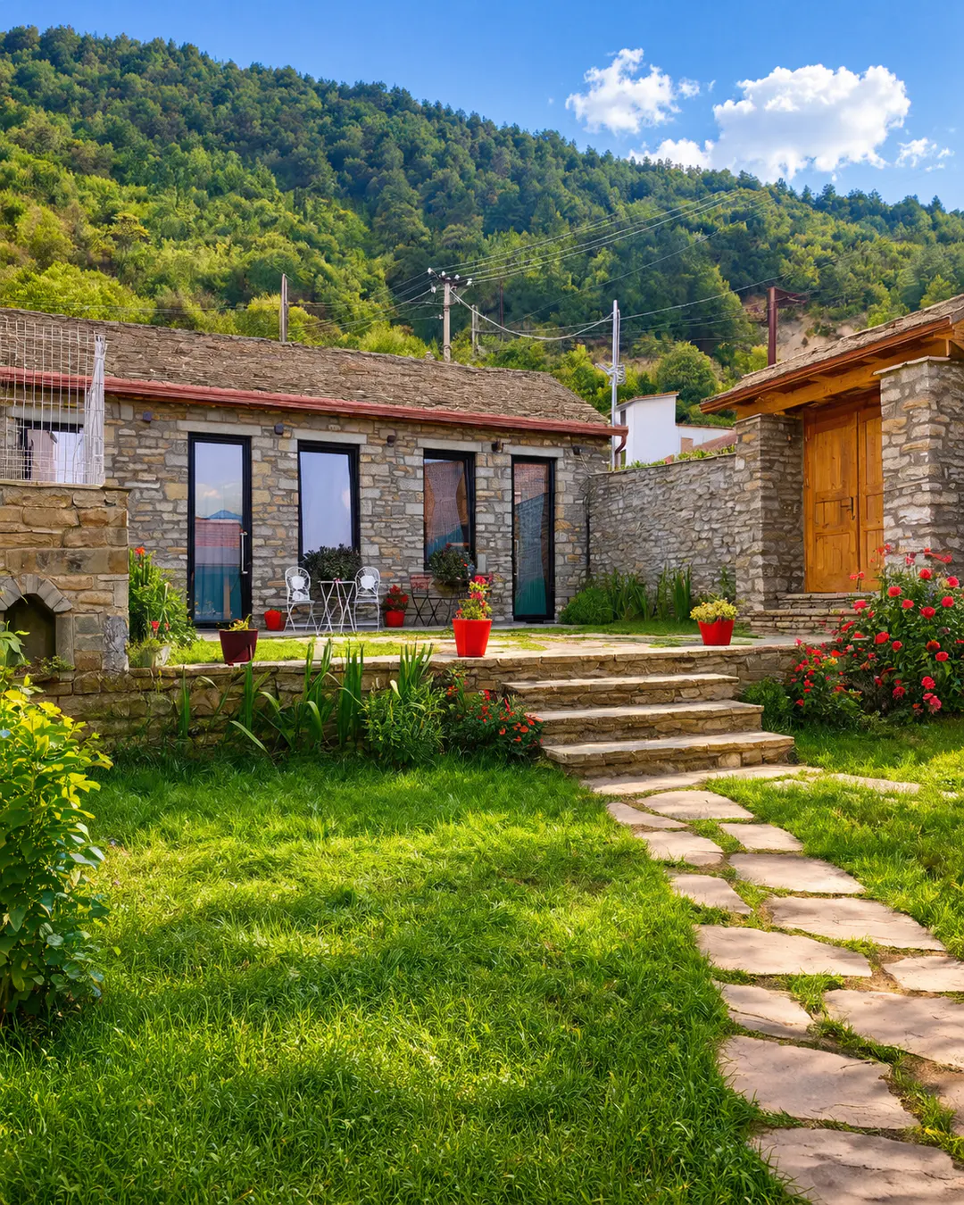 Guesthouse tradizionale in pietra con cortile verde, posti a sedere all'aperto e fiori al Gogo Moustache Guest House di Përmet, Albania