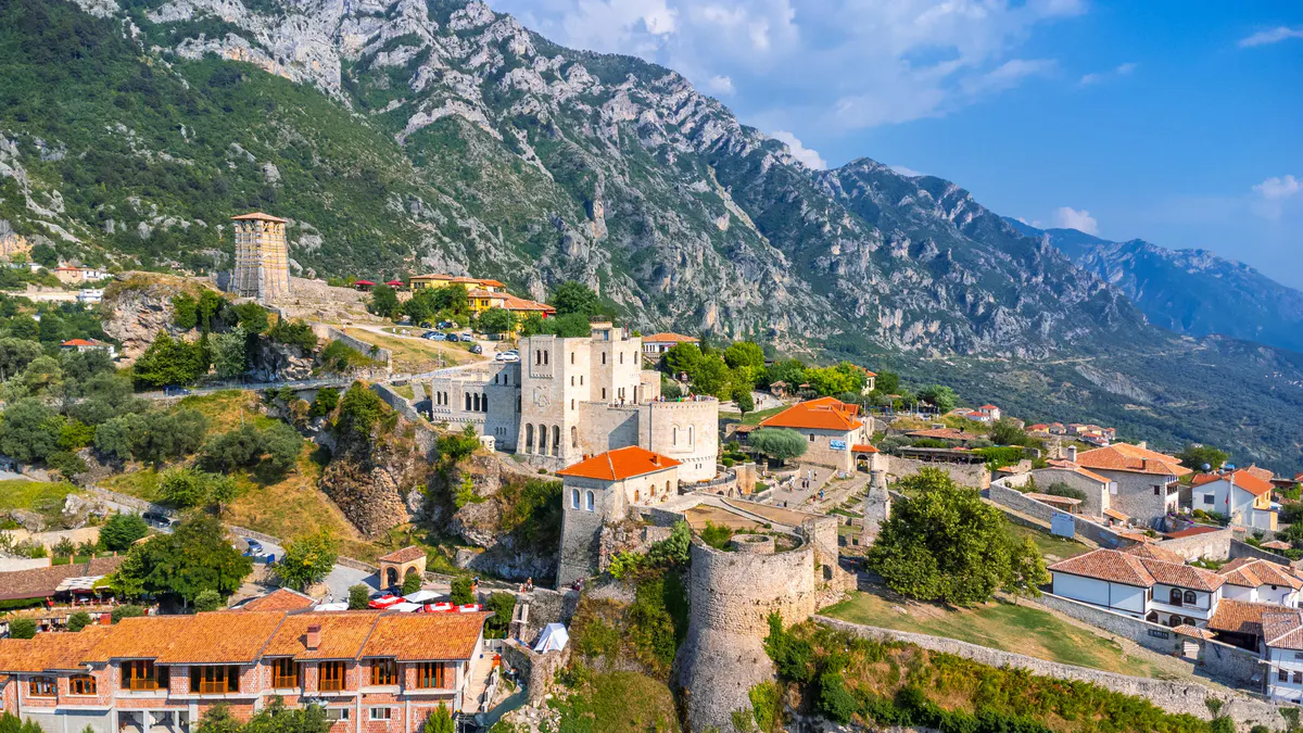 Pamje ajrore e Kalasë së Krujës dhe Muzeut të Skënderbeut, të rrethuara nga shtëpi tradicionale dhe male në Shqipëri.