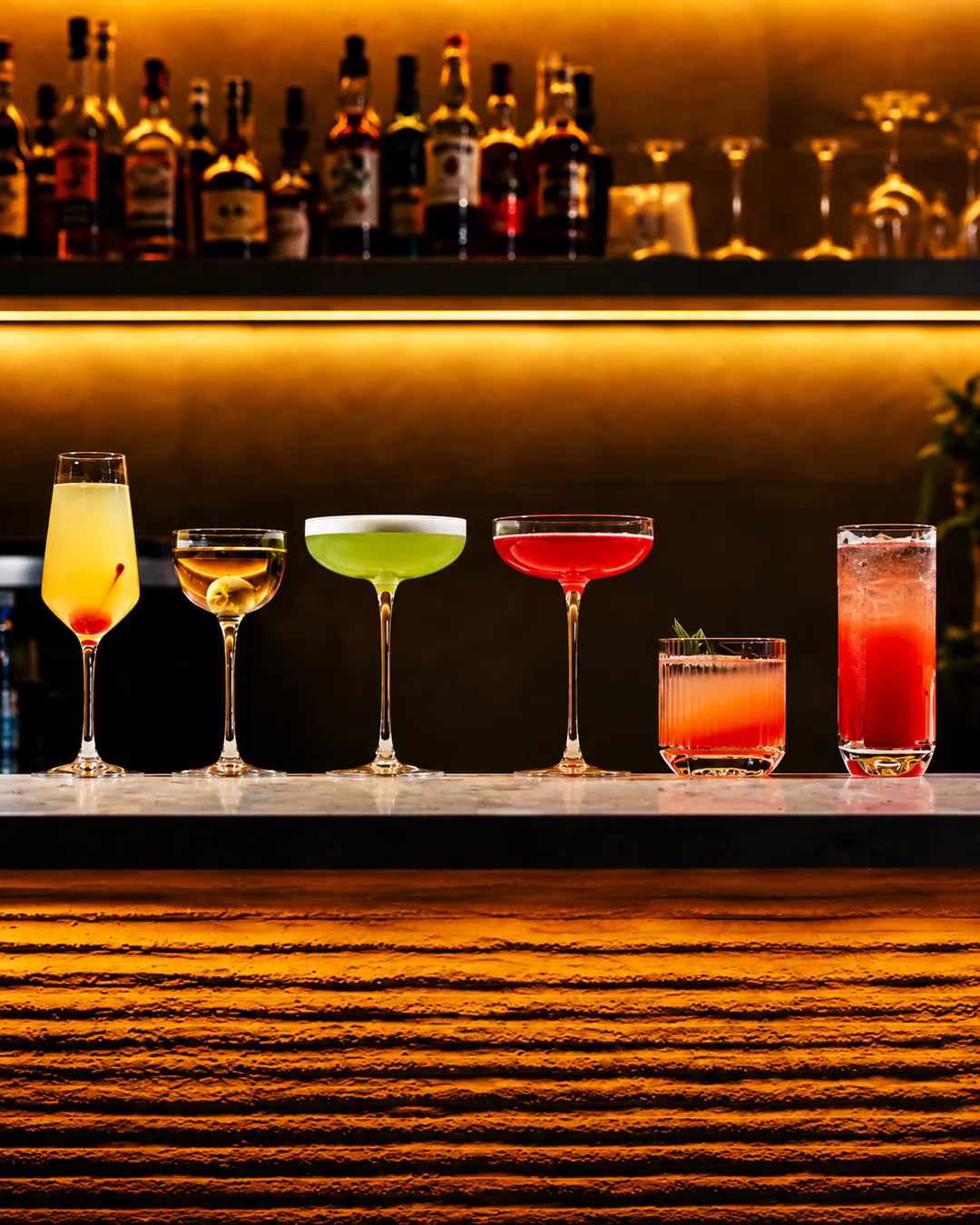 Selection of colorful signature cocktails displayed on the bar counter at La Lumière cocktail lounge in Tirana, with warm ambient lighting.