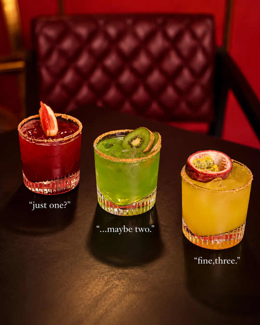 Three colorful signature cocktails in red, green and yellow, garnished with fresh fruit at OBSCURA Cocktail Bar in Blloku, Tirana.