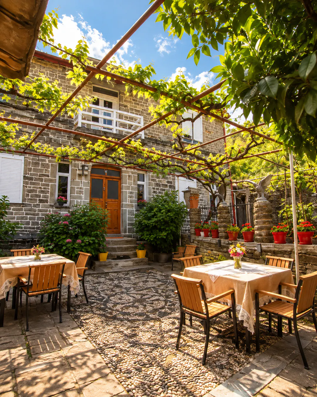 Guesthouse tradizionale in pietra The Mosaic House a Përmet, con caratteristico cortile, posti a sedere in giardino, fiori e viti