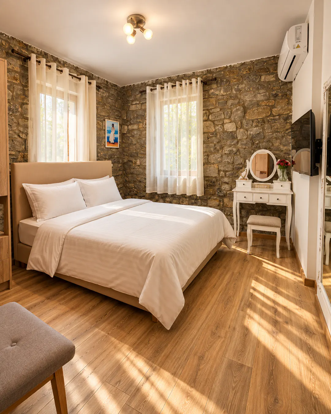 Confortevole camera matrimoniale al The Stone House, con pareti in pietra a vista, biancheria bianca, pavimento in legno e arredamento moderno