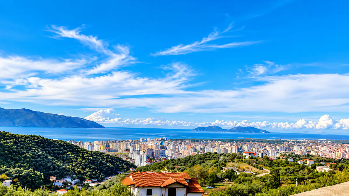 Pamje panoramike e Vlorës, Shqipëri, me qytetin bregdetar, detin blu, kodrat përreth dhe ishujt në largësi.