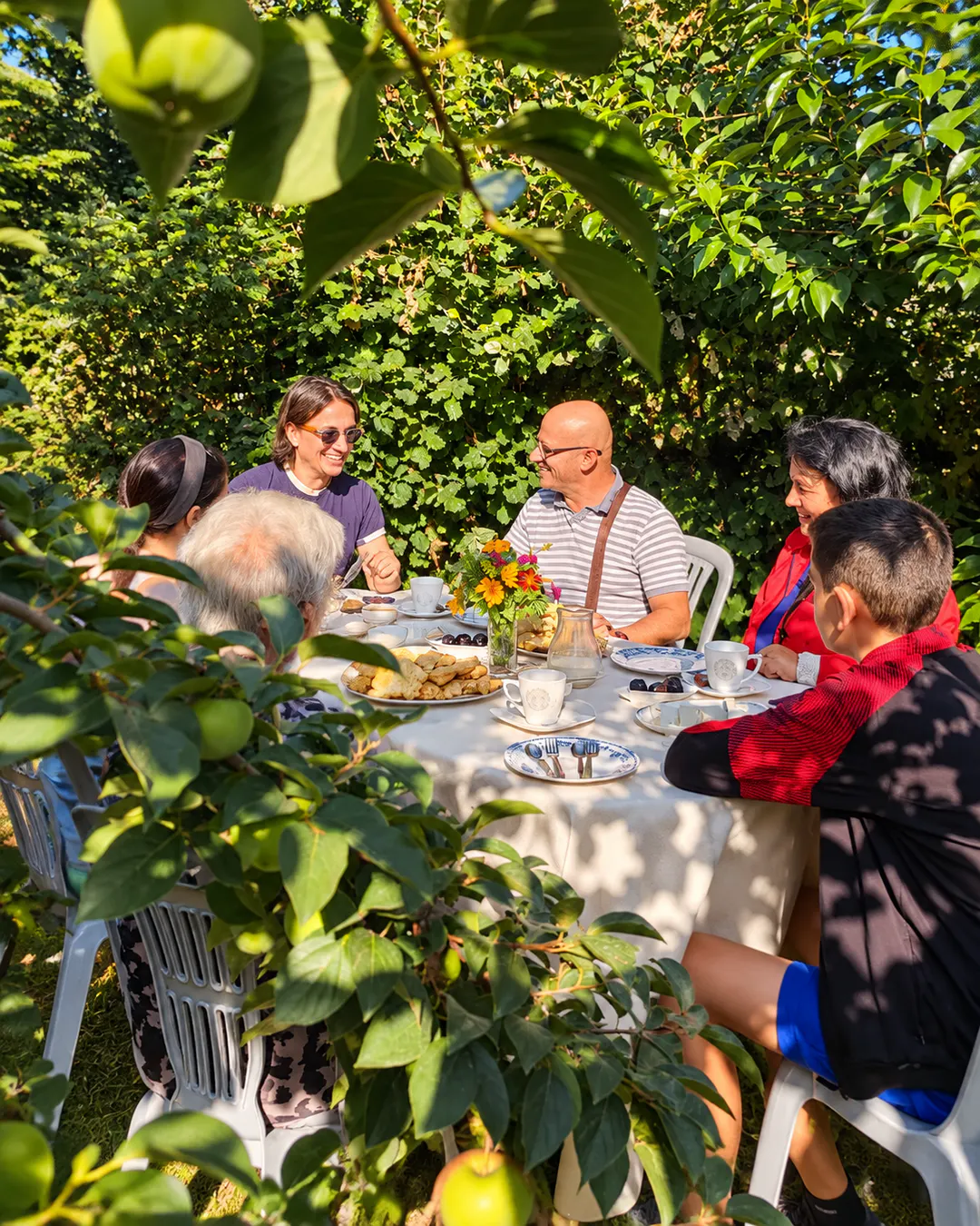 Ospiti che fanno colazione insieme nel rigoglioso giardino verde del Wild River Guesthouse, circondato da alberi e natura