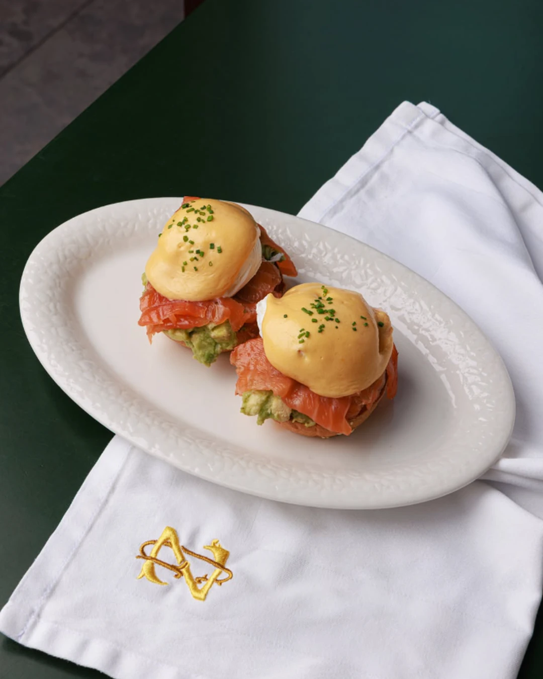 Eggs Benedict with smoked salmon, avocado, and hollandaise sauce served on a white plate at ZABÒ Garden in Tirana.