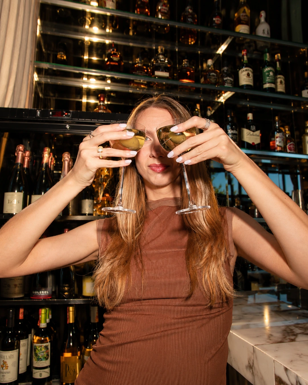 Guest holding glasses of white wine at ZABÒ Garden in Tirana.